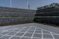 an image of a stone walled outdoor seating wall with a flag pole in the distance