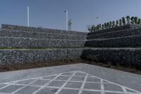 an image of a stone walled outdoor seating wall with a flag pole in the distance