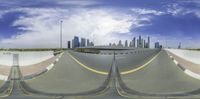 the view of an empty street in front of a city skyline with traffic lights and a traffic light in the distance