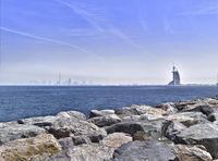 the ocean with large rocks and boats in the background near the city skyline and beach