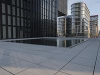 an empty parking lot that has black tiles on the ground and black windows reflecting the sky