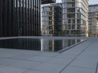 an empty parking lot that has black tiles on the ground and black windows reflecting the sky