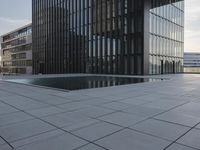 an empty parking lot that has black tiles on the ground and black windows reflecting the sky