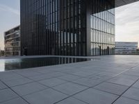 an empty parking lot that has black tiles on the ground and black windows reflecting the sky