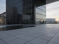 an empty parking lot that has black tiles on the ground and black windows reflecting the sky