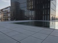 an empty parking lot that has black tiles on the ground and black windows reflecting the sky