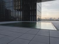 an empty parking lot that has black tiles on the ground and black windows reflecting the sky