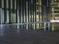 a night view of a pool near a building with a television tower in the background