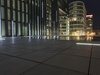 a night view of a pool near a building with a television tower in the background