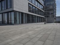 a city street with a stone sidewalk in front of it and two buildings in the background