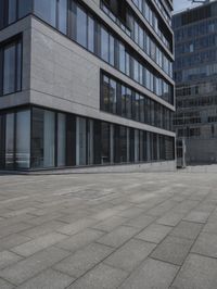 a city street with a stone sidewalk in front of it and two buildings in the background