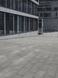 a city street with a stone sidewalk in front of it and two buildings in the background