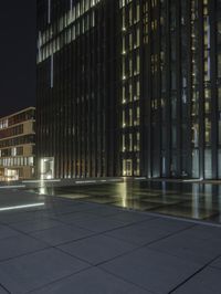 several light strips run along the sidewalk with buildings in the background at night time in the city