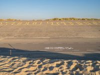 there is sand in the parking lot of an airport with a stop out sign painted on it