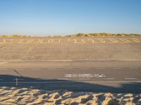 there is sand in the parking lot of an airport with a stop out sign painted on it