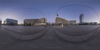 there are two circular mirrors with some buildings in the background at dusk and an abstract structure above