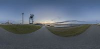 a fish eye view of a beach at dusk with the sun going down in the distance