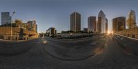 a wide shot of the sun shining over a city street at dusk, on a city highway