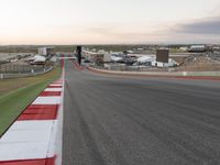 the asphalt course with a red stripe on it at dusk in a city park area