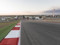 the asphalt course with a red stripe on it at dusk in a city park area