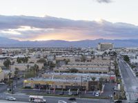 an intersection with many traffic and buildings on it at dusk with mountains in the distance