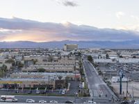 an intersection with many traffic and buildings on it at dusk with mountains in the distance