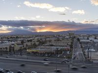 an intersection with many traffic and buildings on it at dusk with mountains in the distance