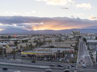 an intersection with many traffic and buildings on it at dusk with mountains in the distance