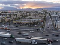 an intersection with many traffic and buildings on it at dusk with mountains in the distance