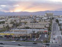 an intersection with many traffic and buildings on it at dusk with mountains in the distance