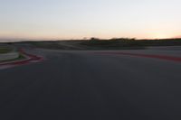 a racing track during the dusk with blurry cars going up it's lap