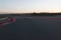 a racing track during the dusk with blurry cars going up it's lap