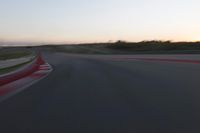 a racing track during the dusk with blurry cars going up it's lap