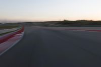 a racing track during the dusk with blurry cars going up it's lap