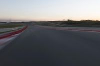 a racing track during the dusk with blurry cars going up it's lap