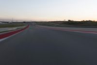 a racing track during the dusk with blurry cars going up it's lap