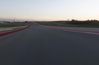 a racing track during the dusk with blurry cars going up it's lap