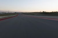 a racing track during the dusk with blurry cars going up it's lap