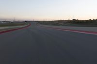 a racing track during the dusk with blurry cars going up it's lap