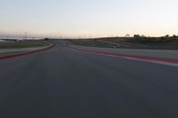 a racing track during the dusk with blurry cars going up it's lap