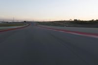 a racing track during the dusk with blurry cars going up it's lap