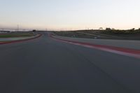 a racing track during the dusk with blurry cars going up it's lap