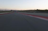 a racing track during the dusk with blurry cars going up it's lap