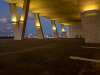 a view of the sky from the roof of an open area with concrete pillars at dusk