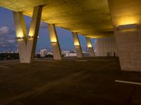 a view of the sky from the roof of an open area with concrete pillars at dusk