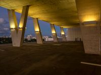 a view of the sky from the roof of an open area with concrete pillars at dusk