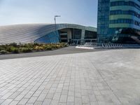 some people sitting on a bench in front of a building on a sunny day with blue skies