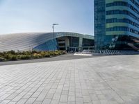 some people sitting on a bench in front of a building on a sunny day with blue skies