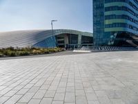 some people sitting on a bench in front of a building on a sunny day with blue skies