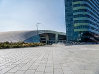 some people sitting on a bench in front of a building on a sunny day with blue skies